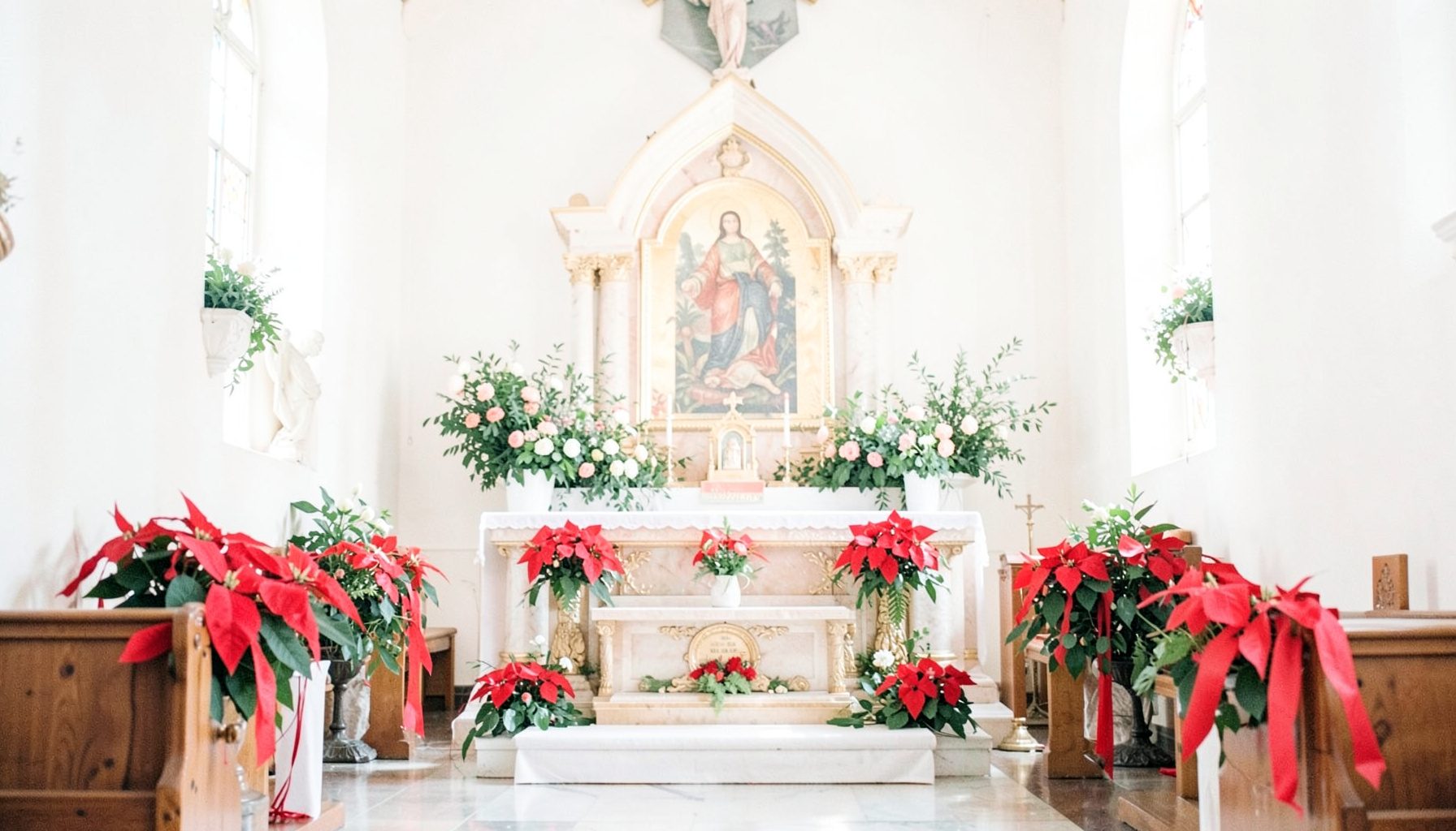 Seasonal greenery and simple floral arrangements adorning the church interior, with poinsettias near the iconostasis
